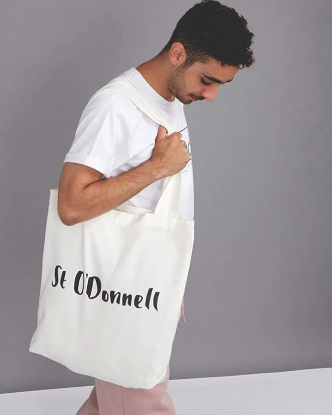 Man carrying a cream St O'Donnell branded tote bag